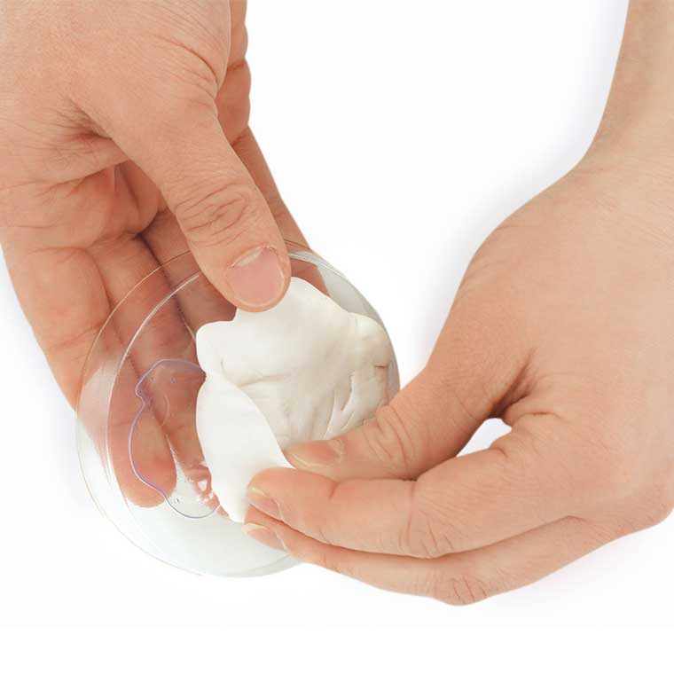 Two hands holding a clear mold and white putty. 