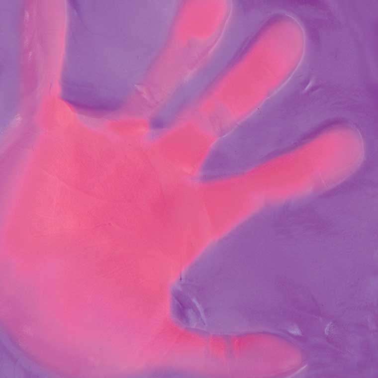 Close up detail of heat sensitive putty that is purple with a pink hand print. 