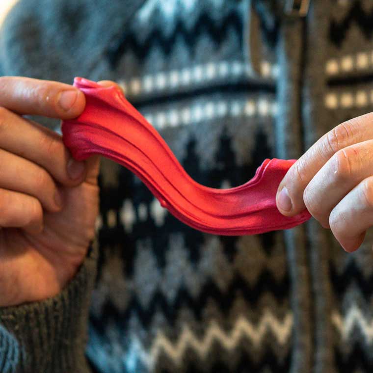 Two hands holding red, apple scented putty.