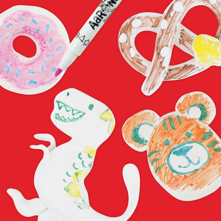 White putty sculpted into the shapes of doughnut, pretzel, dinosaur and tiger, on a red background with a marker.